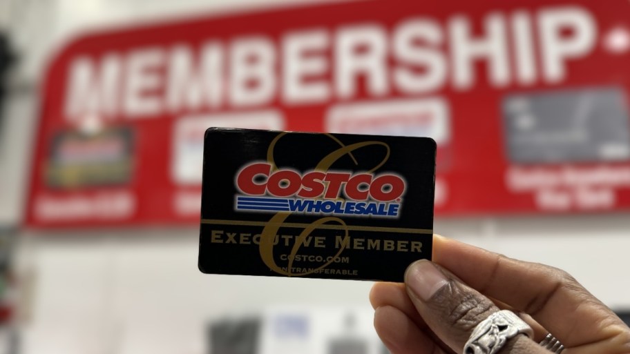 a womans hand holding a costco executive member card
