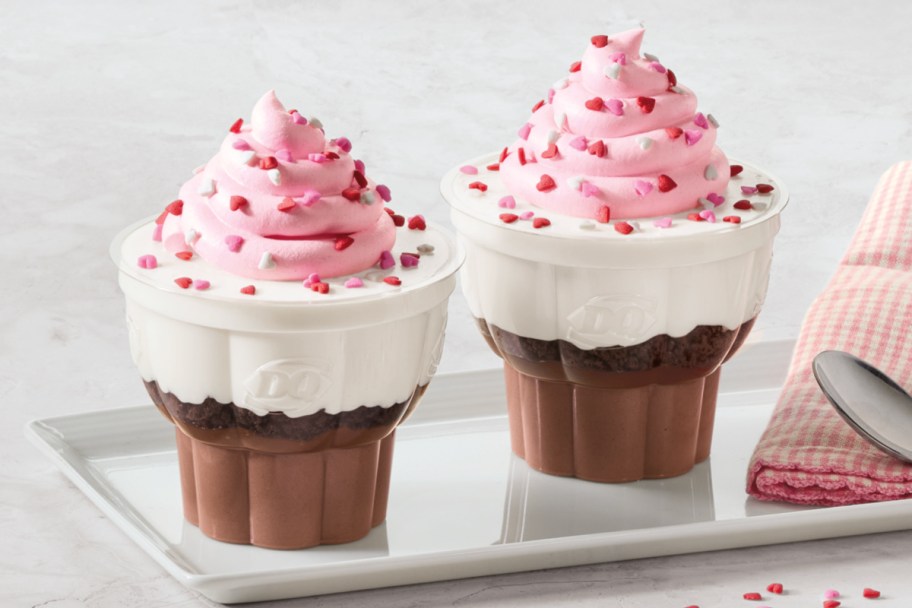 two cupcakes with pink topping over chocolate layer