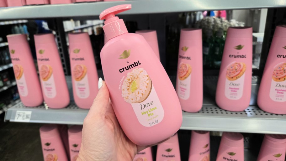 hand holding a bottle of dove crumbl hand soap in front of a store aisle full of more bottles