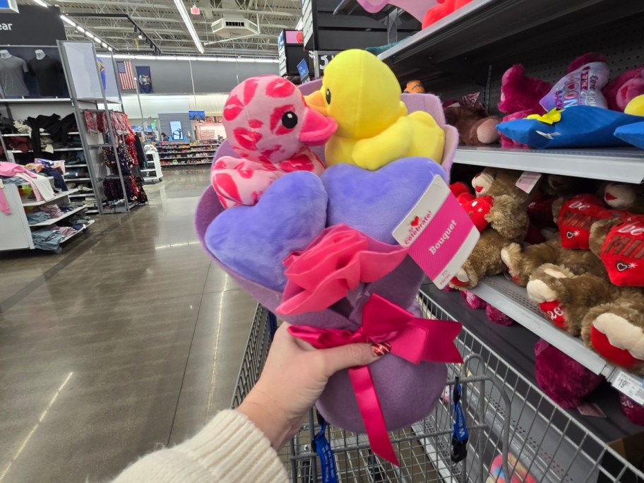 A hand holding up a ducks plush bouquet at Walmart.