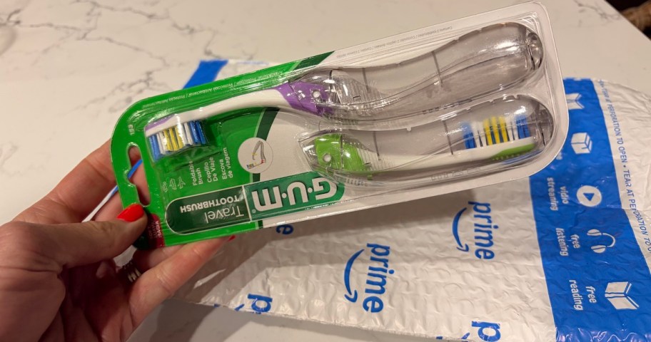 hand holding folding toothbrushes on amazon bag