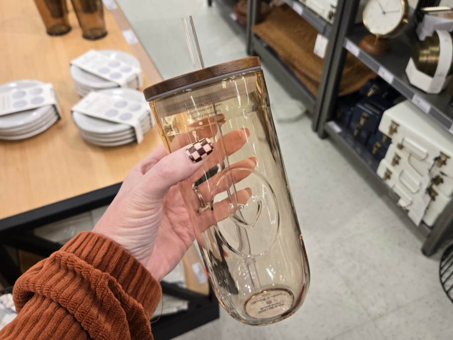 A hand holding up a Hearth & Hand Magnolia glass tumbler.
