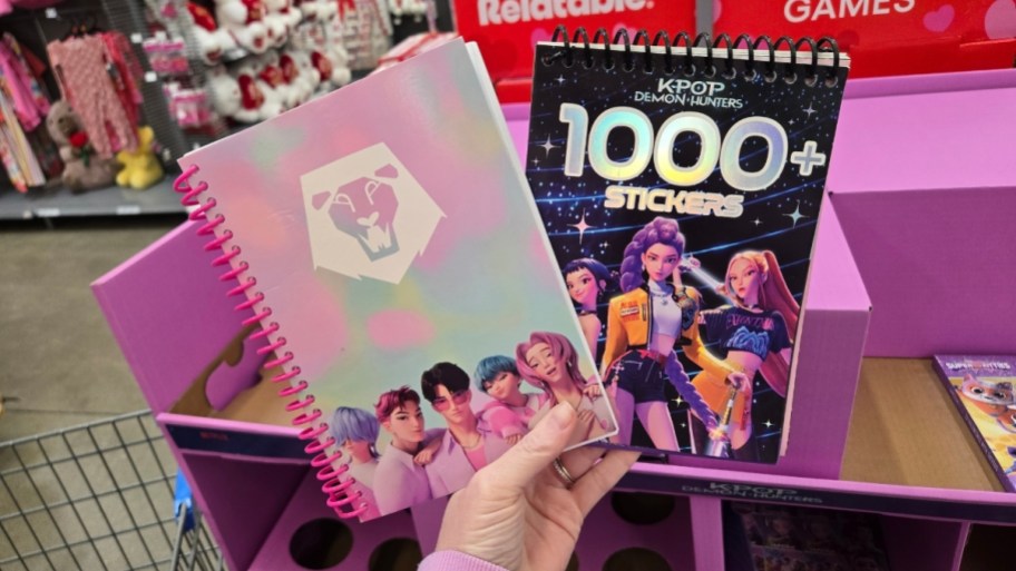 a womans hand holding a journal and a sticker book