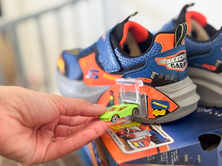 hand removing a tiny plastic car from the shoe garage slot