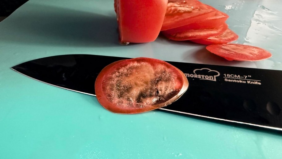 chefs knife blade with thin tomato slice