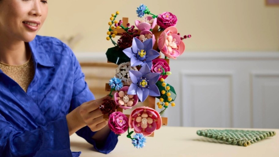 woman holding an assembled lego floral wall building set
