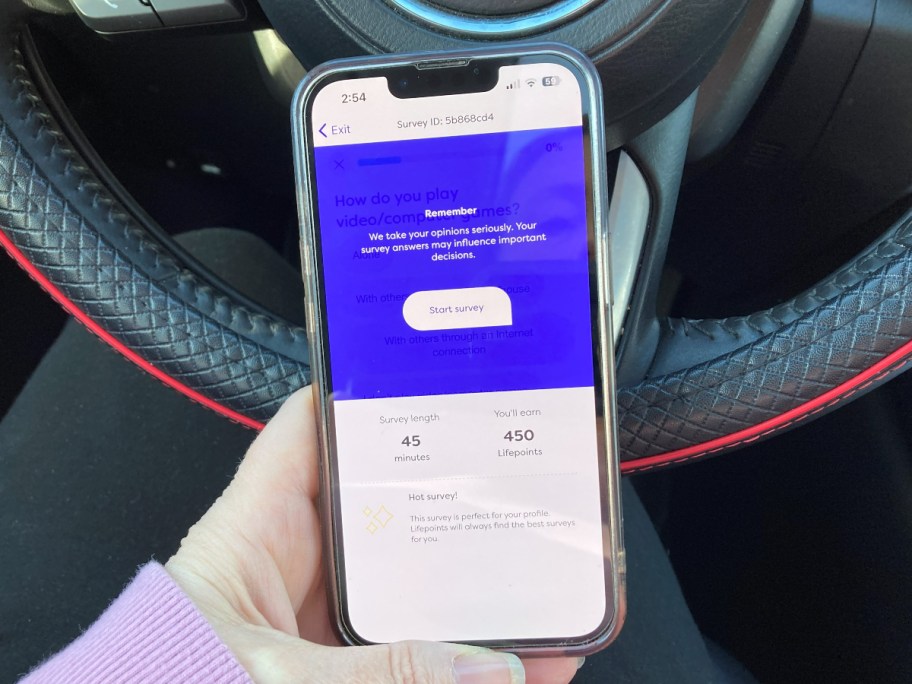 holding a phone in front of a car's steering wheel