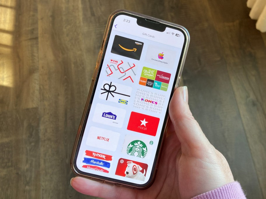 holding a phone showing a list of gift cards