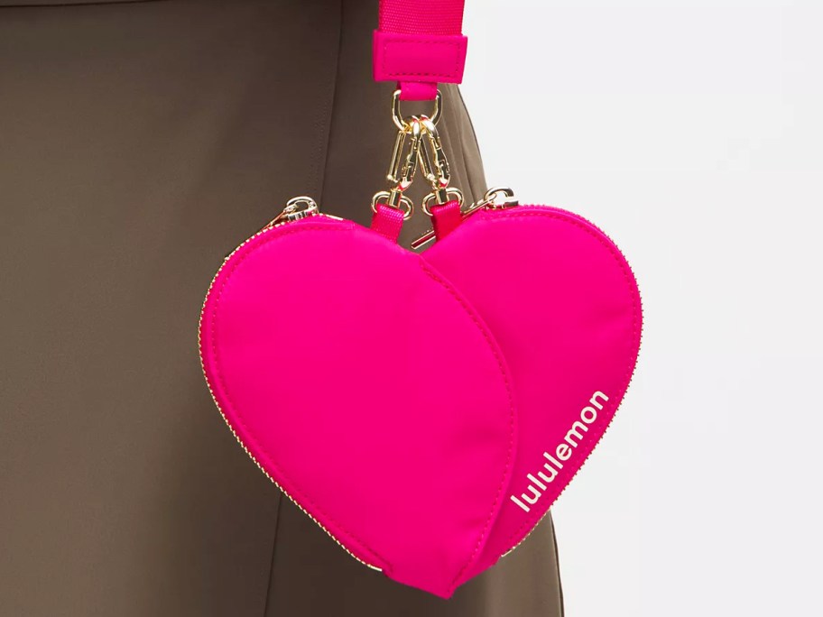 woman holding a bright pink heart shaped wristlet