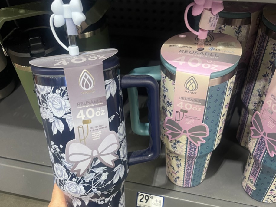 A hand holding up a floral tumbler with a bow straw topper.