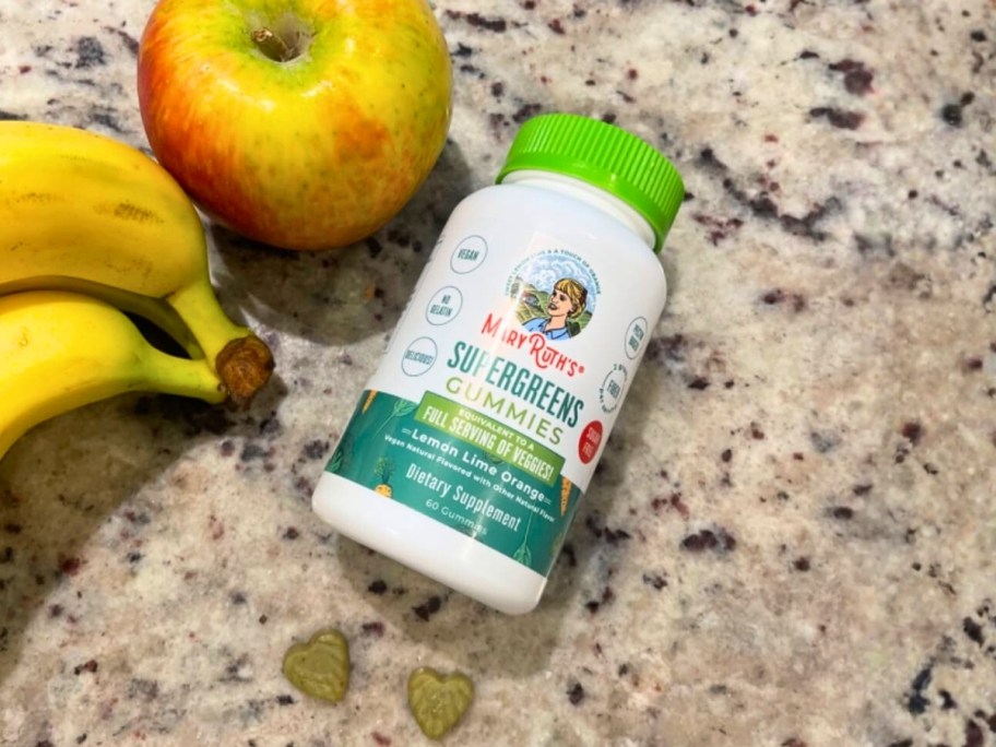 a bottle Mary Ruths supergreens gummies next to fruit on a counter