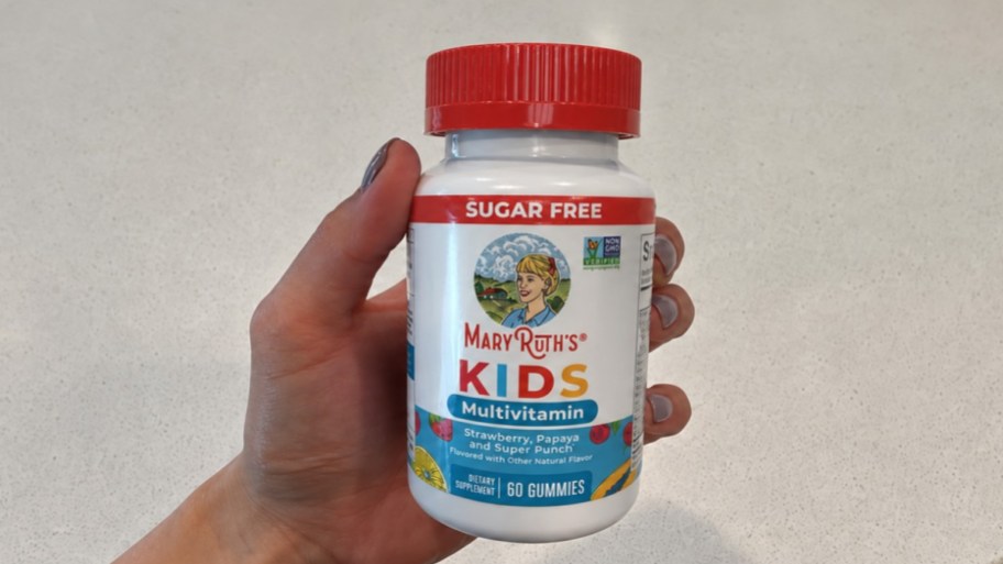 a hand holding a bottle of kids gummy vitamins