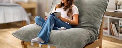 woman sitting in a large lounge chair reading a book