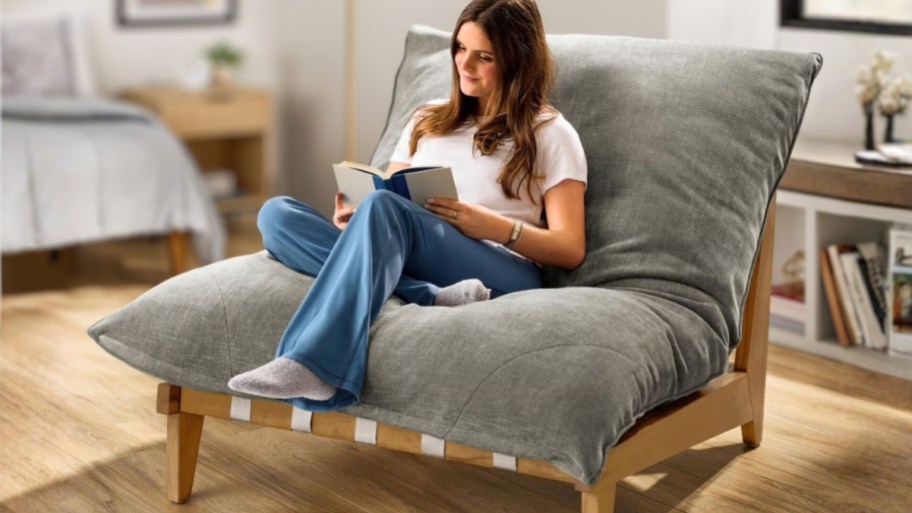 woman sitting in a large lounge chair reading a book