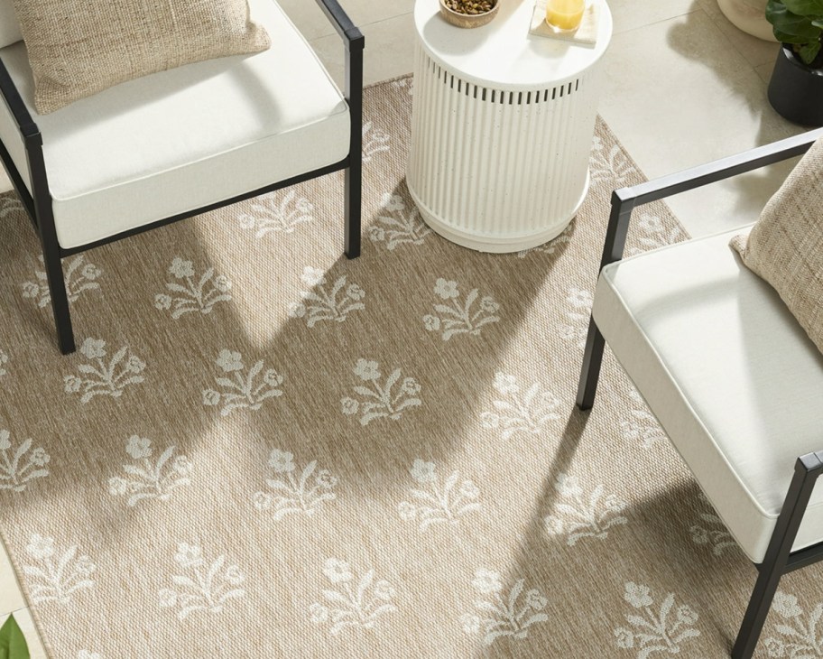 jute floral rug with two white chairs on it