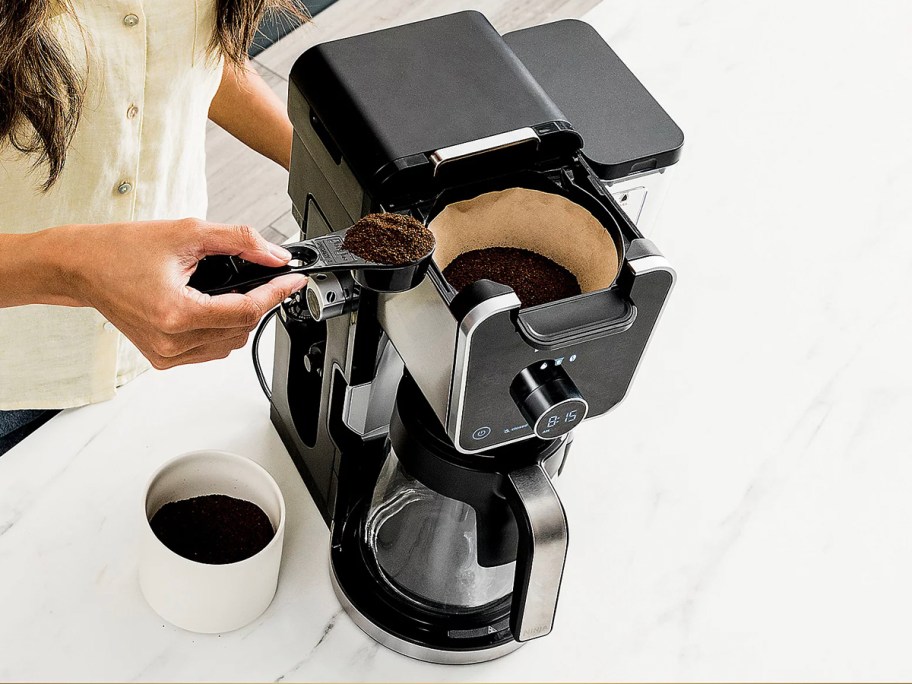 person putting coffee in filter in coffee maker 