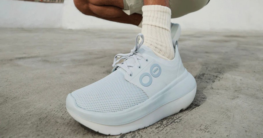 person wearing blue and white oofos shoe