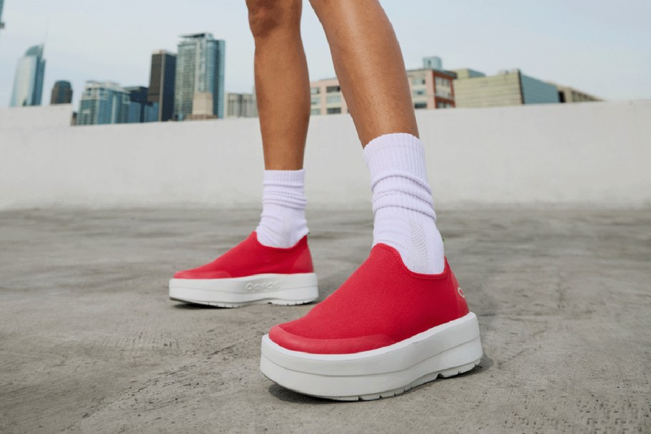 neon pink oofos on a woman's feet 