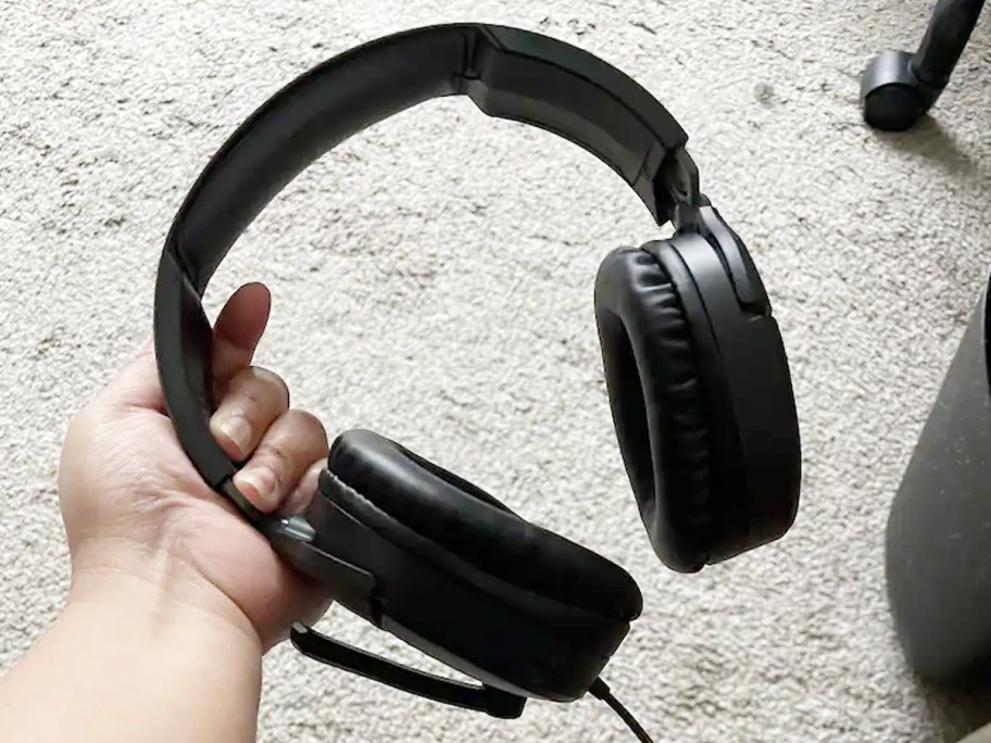 hand holding pair of black headphones 
