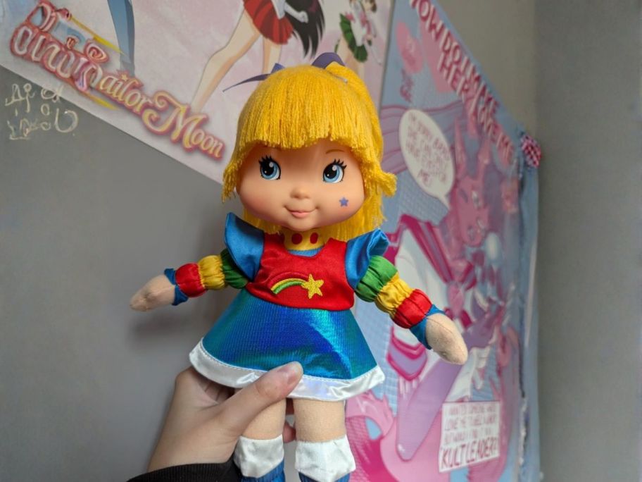 person holding rainbow brite doll in bedroom