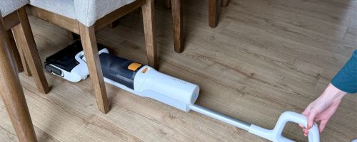 person using lie flat feature of Roborock All-in-1 Vacuum underneath dining room chair