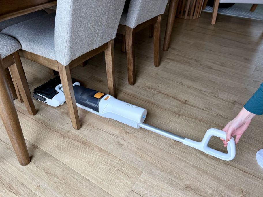 person using lie flat feature of Roborock All-in-1 Vacuum underneath dining room chair