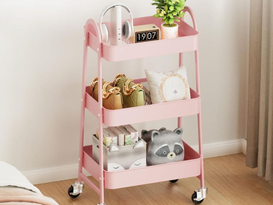 Pink rolling cart with items inside of it in the living room 