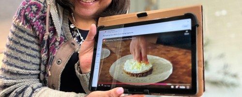smiling woman holding a tablet showing a recipe video