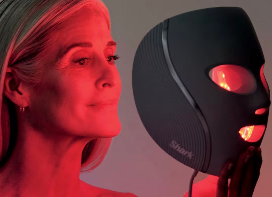woman holding red light therapy mask in front of face