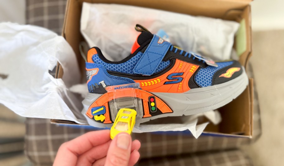 hand inserting a tiny plastic car into the shoe slot