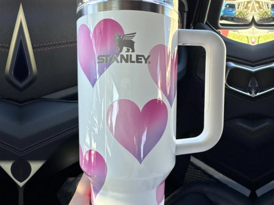 close up of white heart stanley tumbler in car