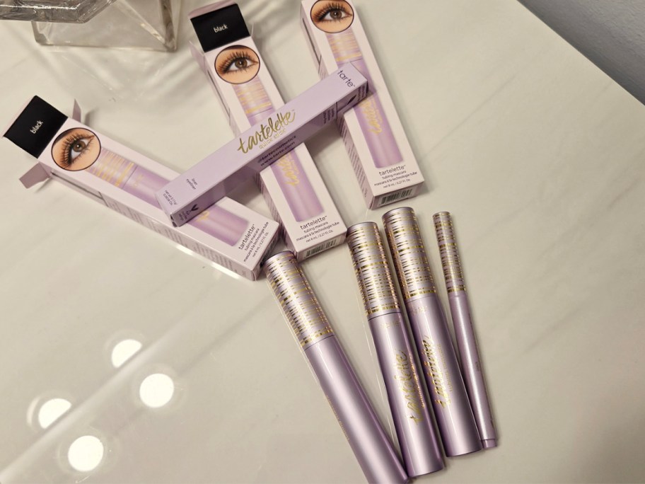 three tartlette mascaras and eyeliner with boxes on table