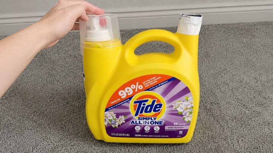 a womans hand reaching for a bottle of laundry detergent