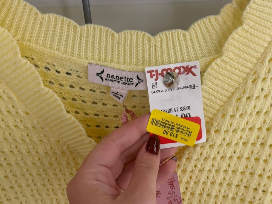 hand holding tag on yellow sweater in tj maxx store