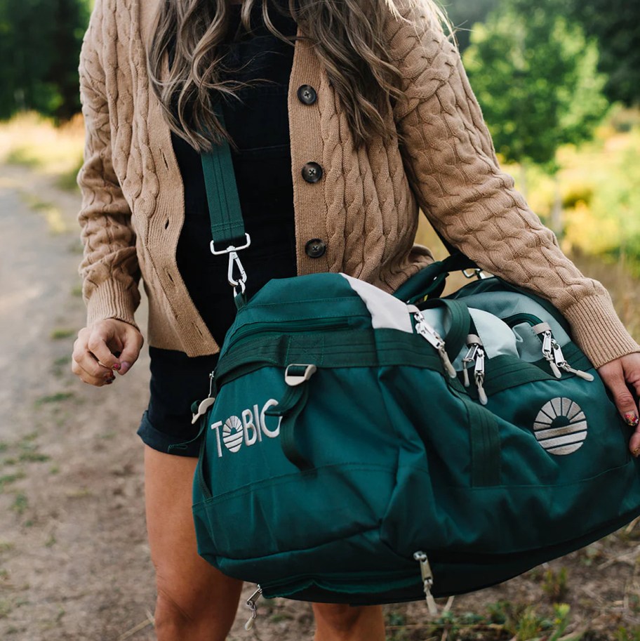 woman holding teal colored tobiq bag on shoulder