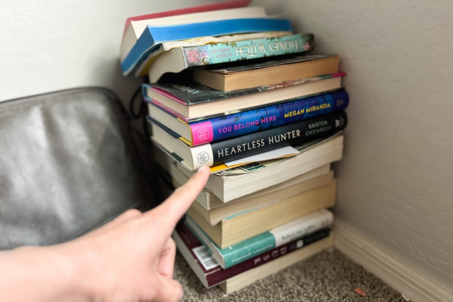 finger pointing at stack of books