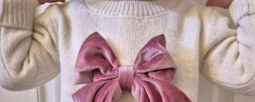 Little girl wearing white sweater with pink bow