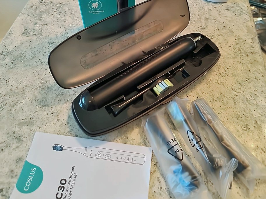 black electric toothbrush in its case with brush heads on bathroom counter