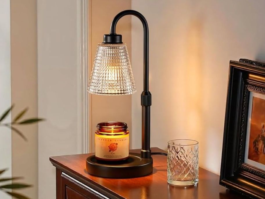 A black candle warmer with a glass shade on a dresser