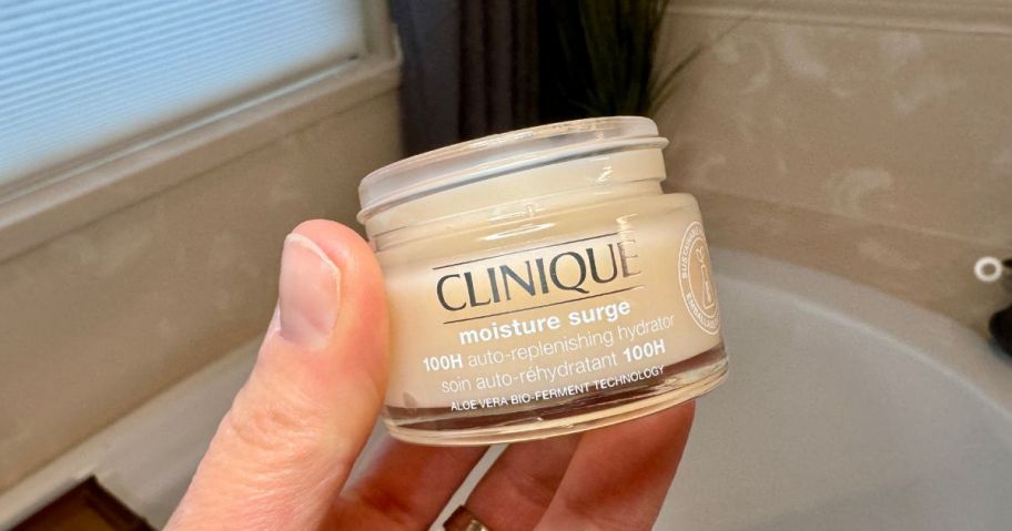 Hand holding a jar of Clinique Moisture Surge