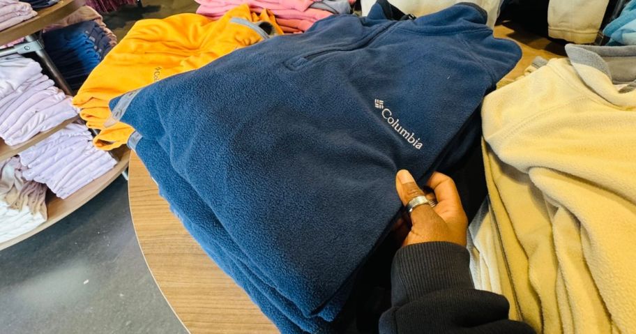 Hand holding a Columbia jacket on display at the store