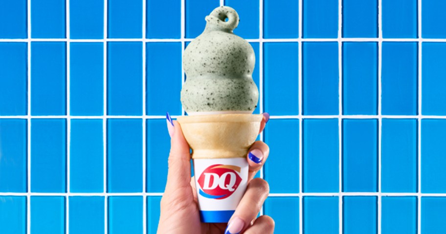 hand holding up a dairy queen dipped cone with a blue tile background