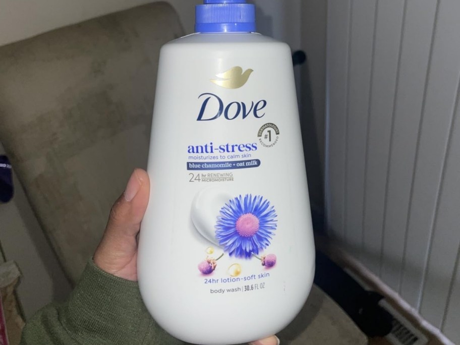 person holding a bottle of dove anti-stress body wash