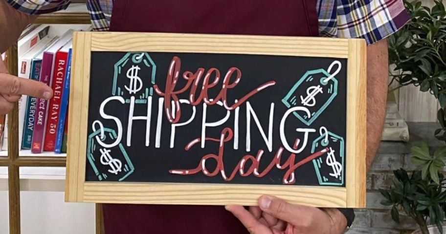 QVC presentor holding a free shipping day chalkboard sign