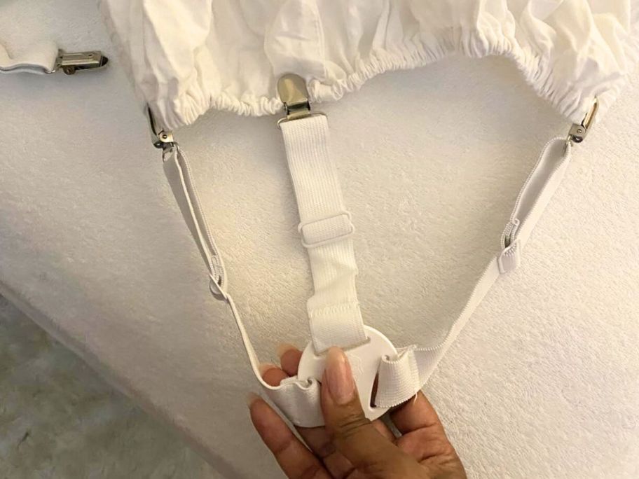 hand holding GORILLA GRIP Bed Sheet Holders 4-Pack attached to fitted sheet