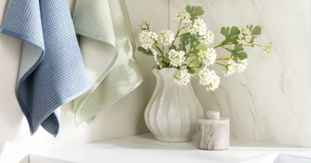 White artificial flowers, inside white ceramic pot on countertop