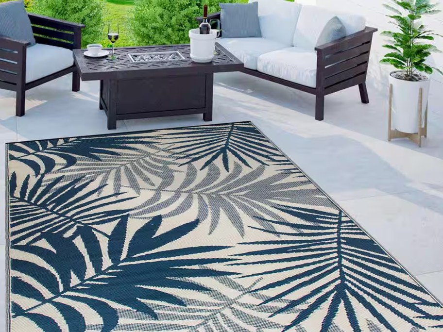 blue palm print outdoor rug in front of a patio set