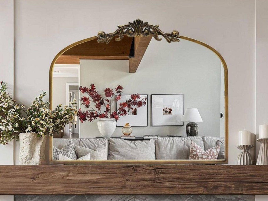 Sxiawe Ornate Baroque Arched Wall Mirror in gold sitting on mantle with flowers next to it