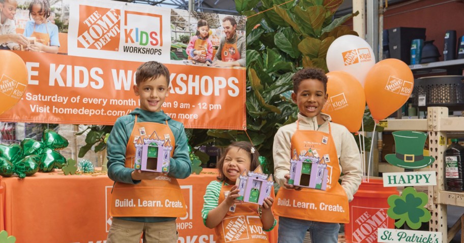Kids holding up crafts and smiling at a Home Depot kids workshop