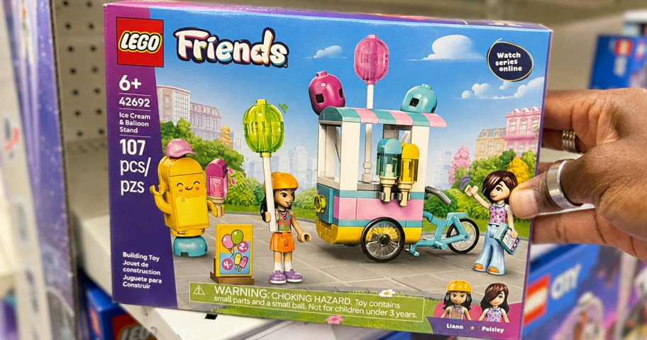 hand holding box to LEGO Friends Ice Cream & Balloon Stand on store shelf
